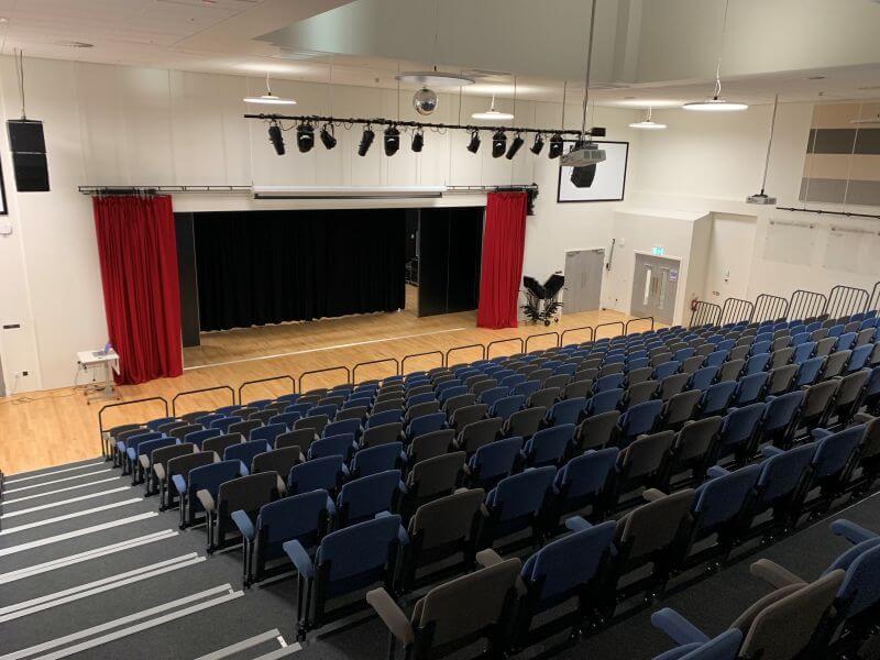 View from the back of the assembly hall looking down on rows of seats looking onto a stage area