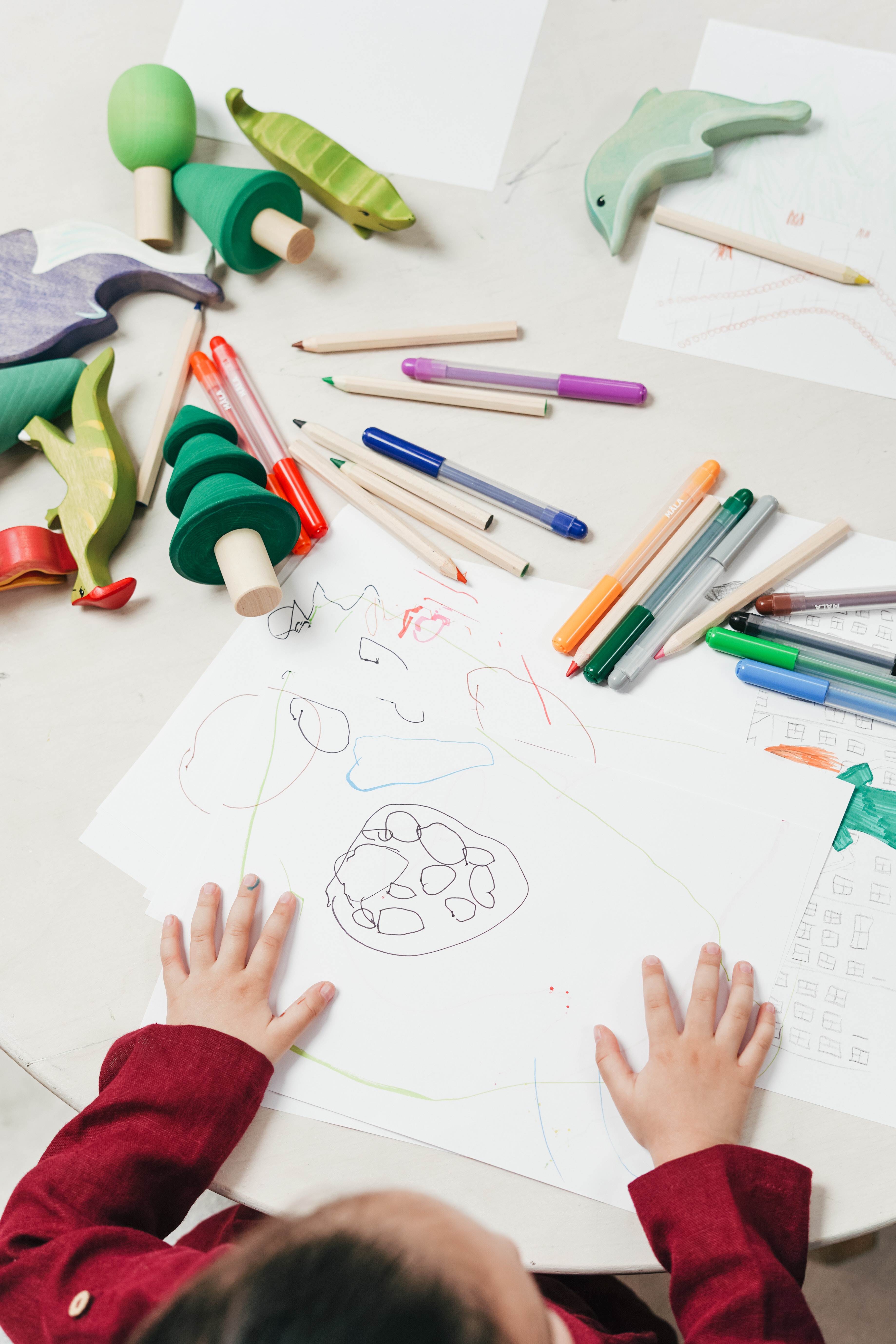 Child sitting at table with crayons and pencils