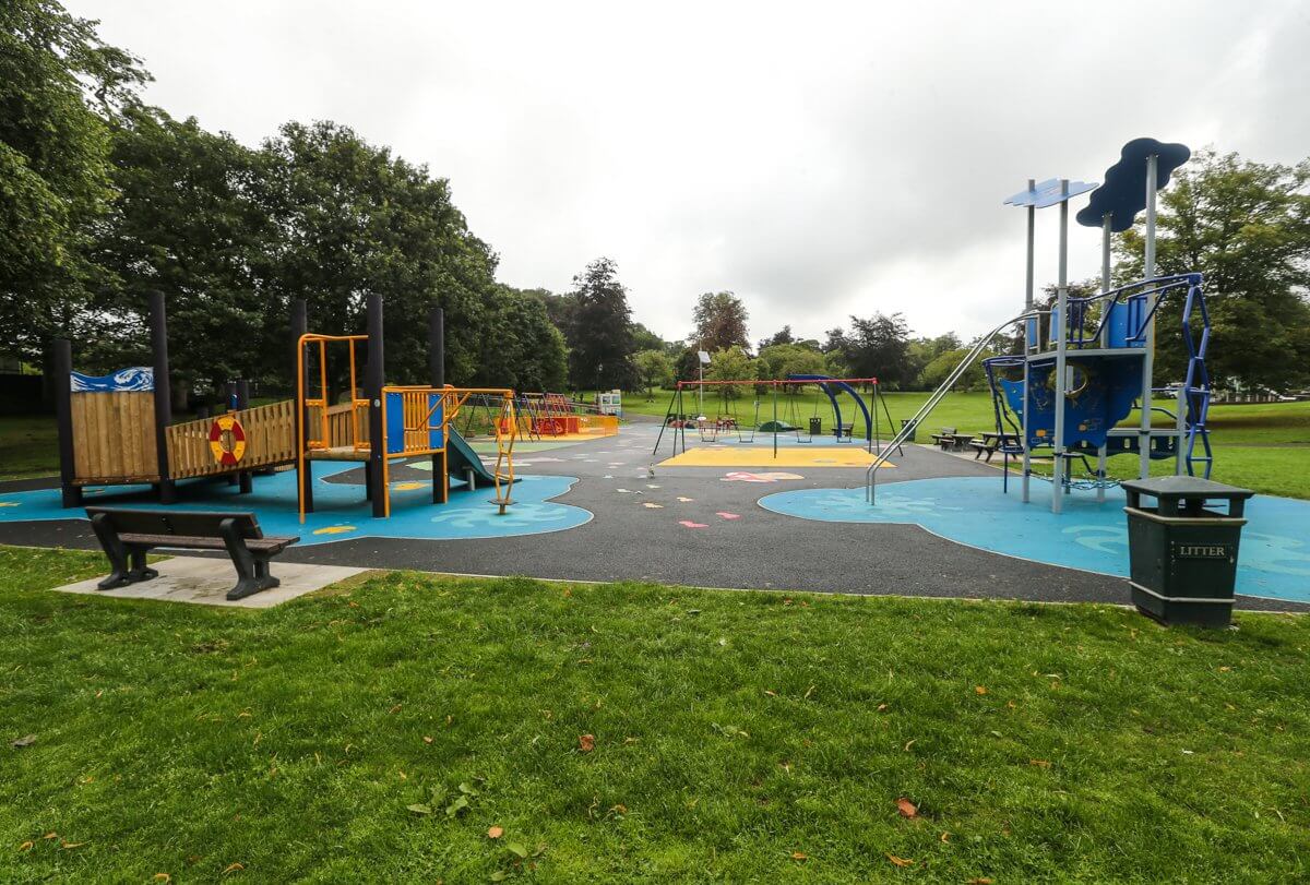 Outdoor playground with colourful climbing frames, slides, and swings set in a grassy park. - Fife's outdoor play areas re-opening