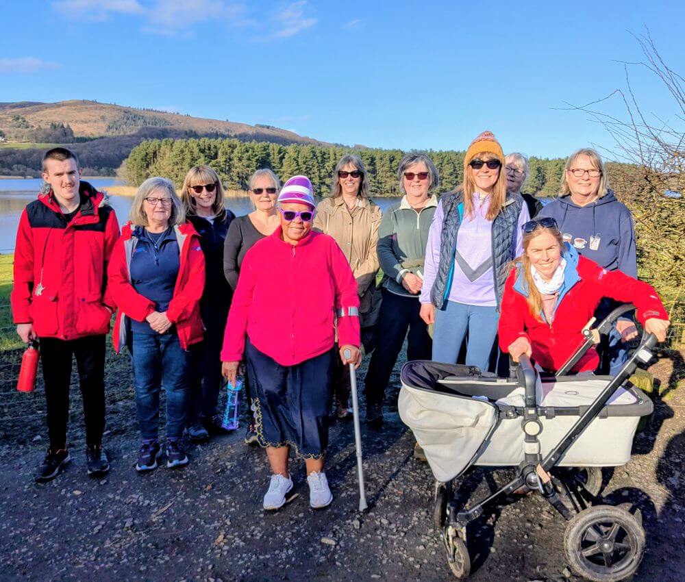 Group of walkers, in front of loch with trees in background - Join the Active Fife May Walking Challenge