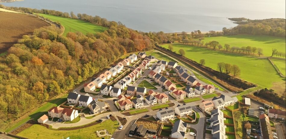 Birds eye view of Main Street, showing lots of houses surrounded by green fields and trees