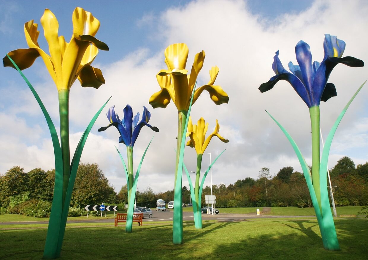Five large sculptures of yellow and blue iris flowers on a roundabout Five large sculptures of yellow and blue iris flowers on a roundabout
