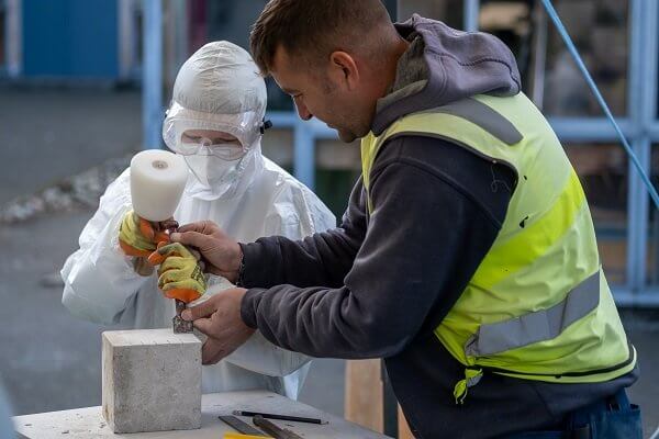 Stonemason assists a pupil to tool a limestone block - Traditional skills a hit with Inverkeithing High School pupils