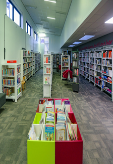 the interior of a library with bookshelves, tables, and a grey carpet