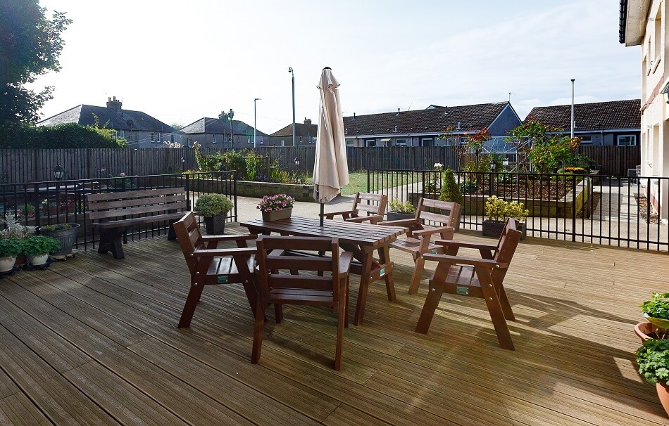 Communal outdoor bench area with table and chairs on decking