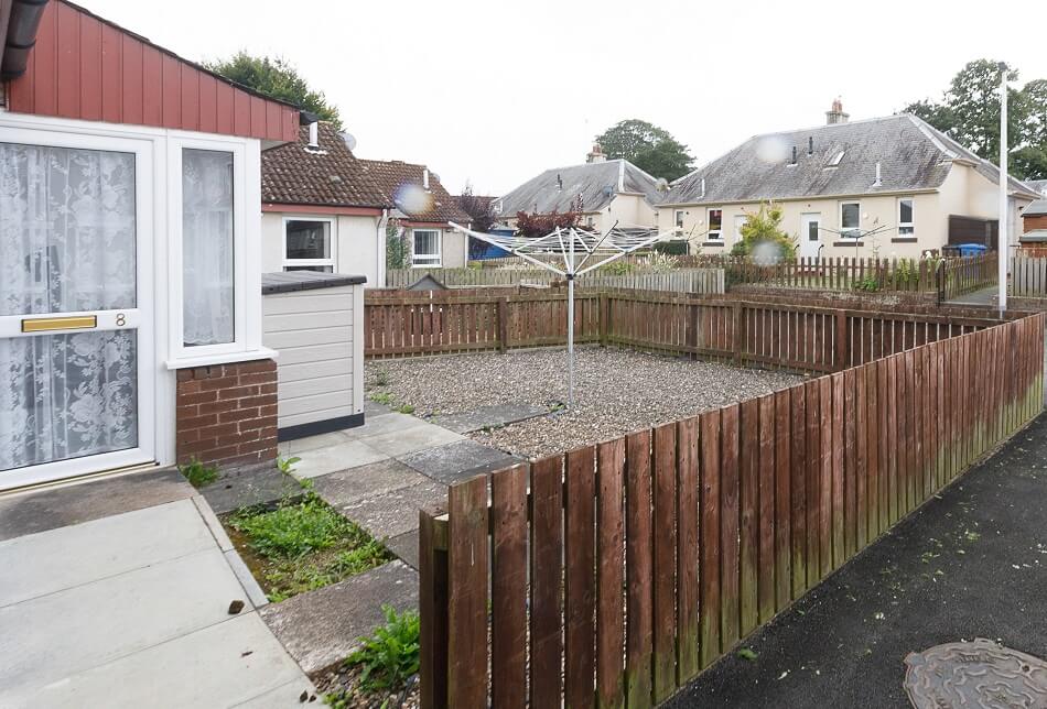 Example of garden of bungalow, with rotary clothes drier and chipped area
