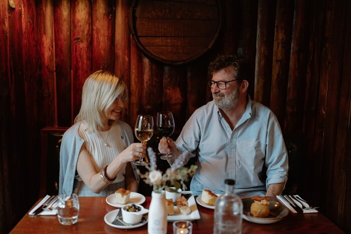 A lady and man sit at a dining table enjoying food and drinks at The Crusoe at Lower Largo
