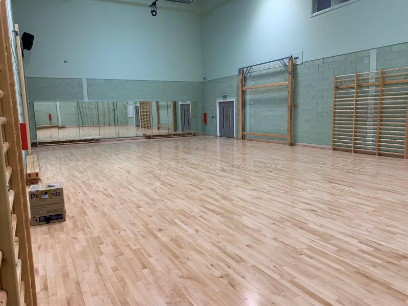 Image of a gym hall with mirrors spanning across the top wall and monkey bars along the adjacent wall
