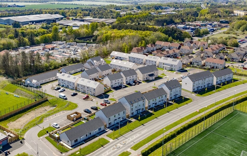 Birds eye view of white houses with grey roofs, surrounded by greenery Birds eye view of white houses with grey roofs, surrounded by greenery