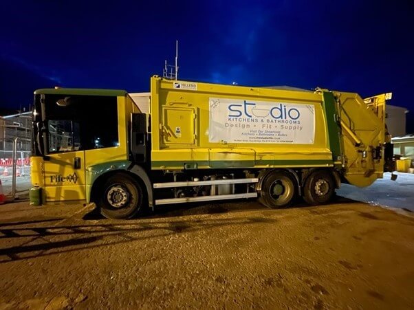 Big yellow bin lorry with Studio Kitchens advert on the side Big yellow bin lorry with Studio Kitchens advert on the side