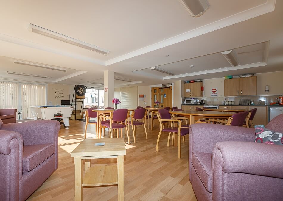 Communal lounge and kitchen area, with soft chairs and dining tables and chairs