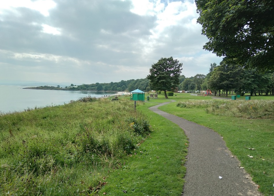 Winding path through a grassy park leading to the beach