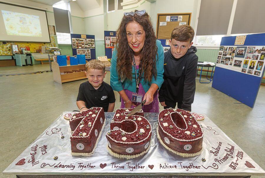 Headteacher Tracey McDougall with 2 school pupils about to cut a 150th birthday cake