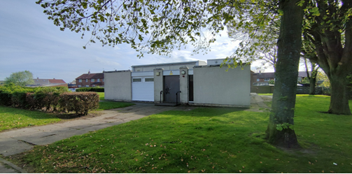 Front view of Whitehouse community centre with visible trees ad green grass surrounding the building