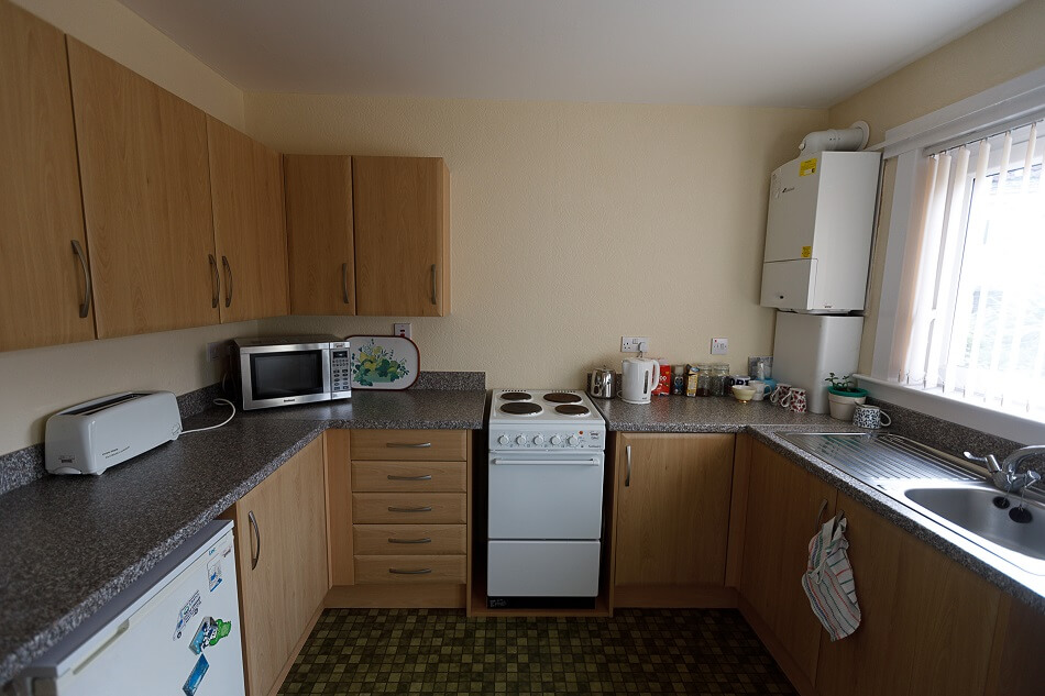 Communal kitchen at Castle Park, with sink area, fridge, and cooker, from a face-on perspective