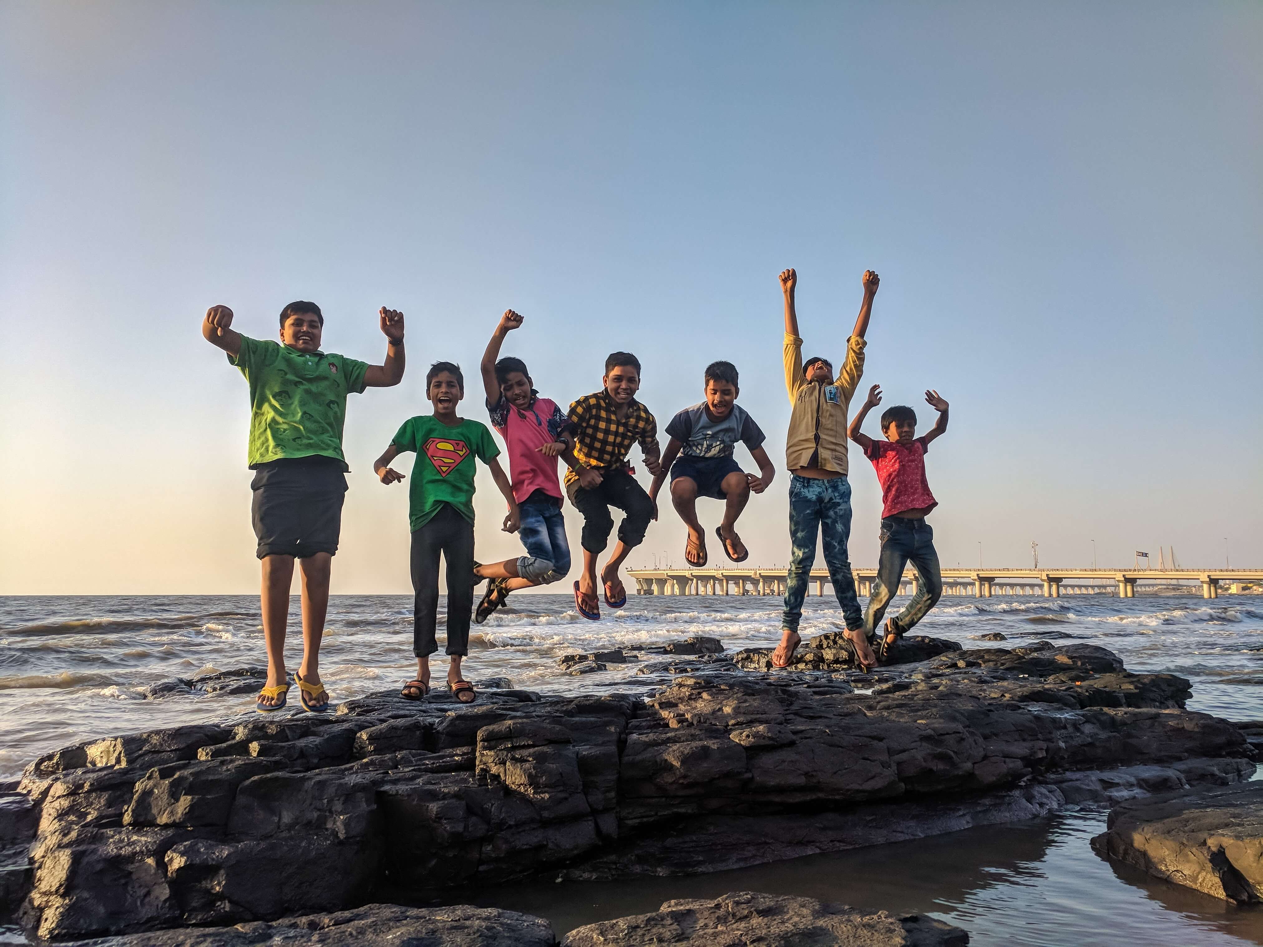 Children and young people jumping from a rock in the sea