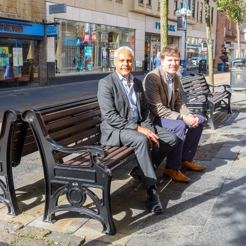 Sunil Varu and Cllr James Calder sitting on new benches on Dunfermline High Street new benches on Dunfermline High Street