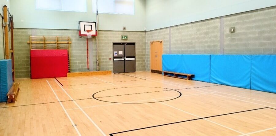 gym hall A gym with wooden floors. Court lines mark the playing area. Padded walls line the sides.