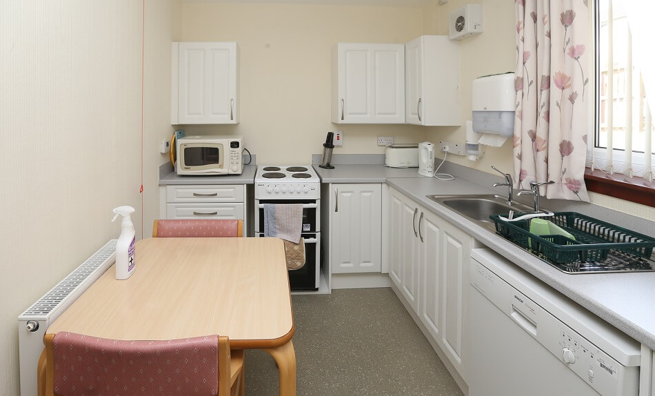 Small communal kitchen and dining area at Elm Place, with table and two chairs