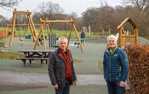 Play park at Ravenscraig with new play equipment in the background. Two men in the foreground.