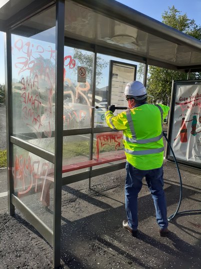Graffiti being washed off a bus stop