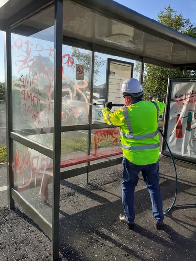 Graffiti being washed off a bus stop