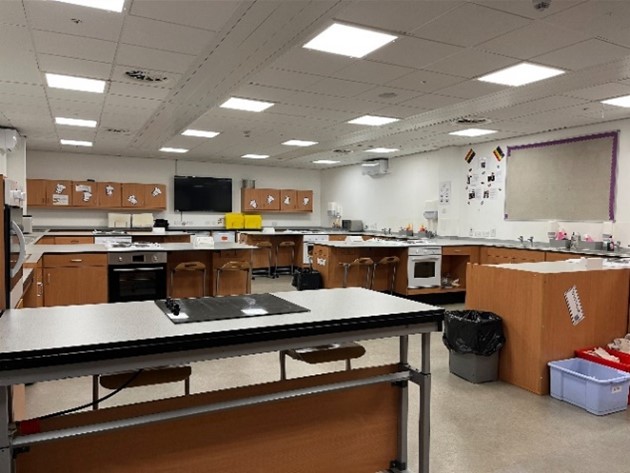a classroom with multiple workstations, each equipped with ovens, sinks, and storage units