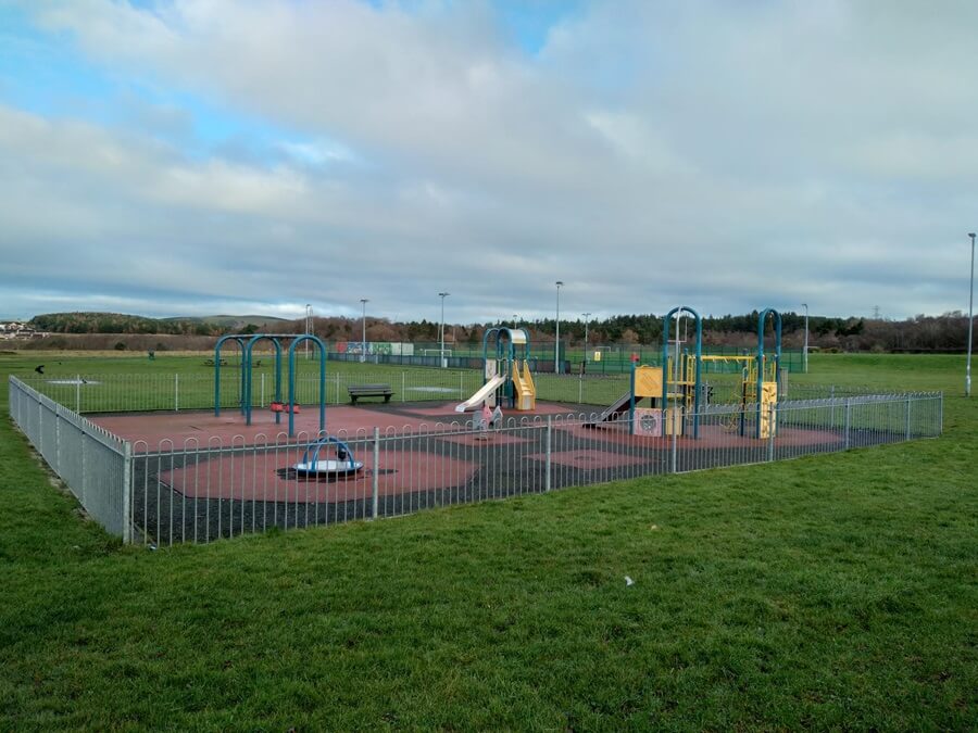 Play park equipment in Duloch park enclosed in metal fence and gate