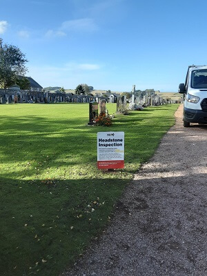 Cemetery with noticeboard saying that headstone inspections are taking place