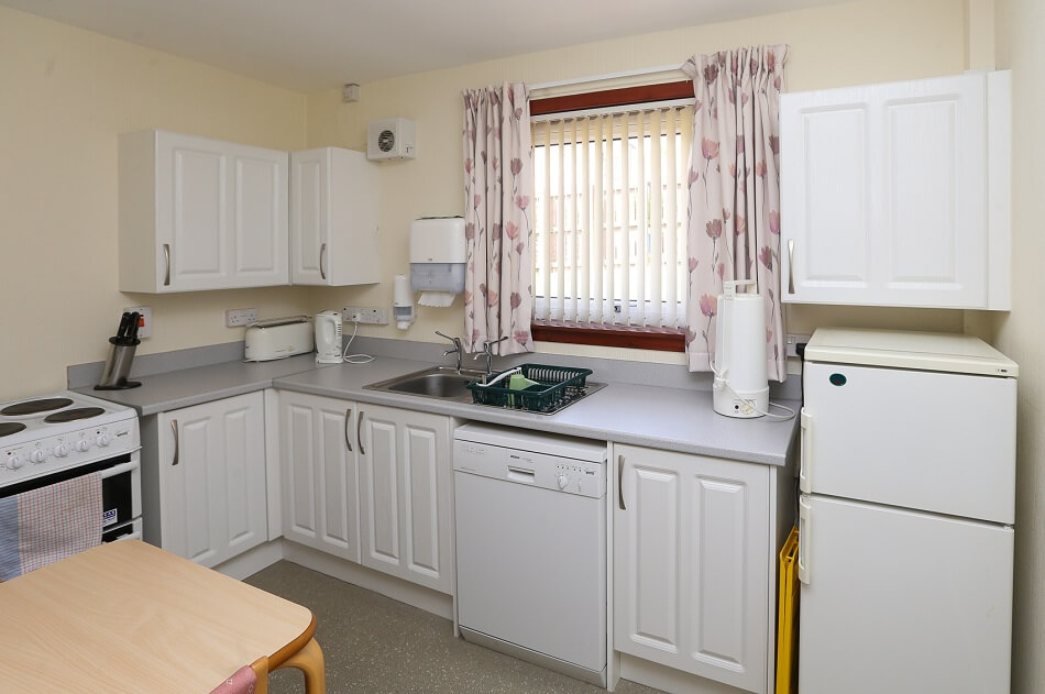Alternative view of communal kitchen and dining area at Elm Place, with sink area and six cupboard units