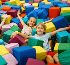Soft-Play.jpg Children lying and playing in a large foam pit filled with colourful soft blocks
