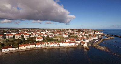 Arial view of Pittenweem taken from the sea showing the harbour and village. It's a bright day with a band of cloud showing in the left hand, upper corner of the picture. 
