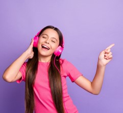 Party.jpg Person wearing pink headphones and a pink shirt, holding one headphone with one hand and pointing outward with the other against a purple background