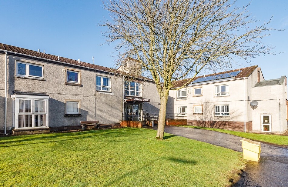 Exterior of the front of the building at Meldrum Court, with gardens and communal path