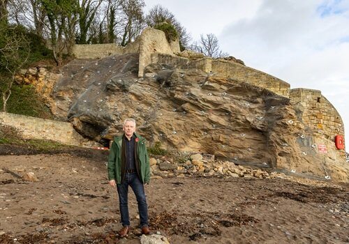 Councillor Ian Cameron standing in front of Dysart rock face where stabilisation works in now complete