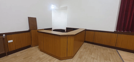 A corner of a room featuring a wooden L-shaped counter, wood wainscoting, and a light wood floor.
