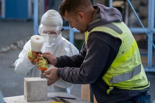 Stonemason assists a pupil to tool a limestone block
