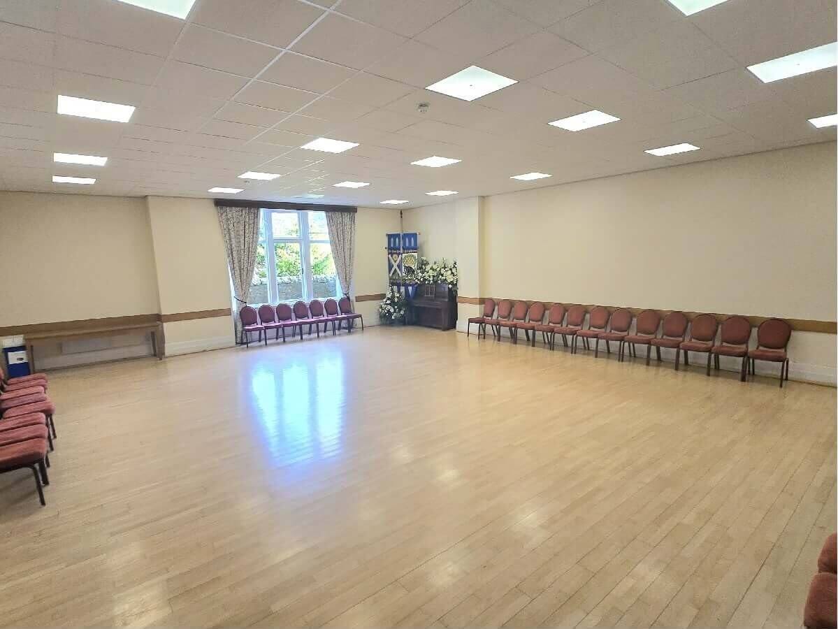 Small hall St Andrews Town Hall Large empty room with wooden flooring, rows of chairs around the walls, and a window with curtains at one end