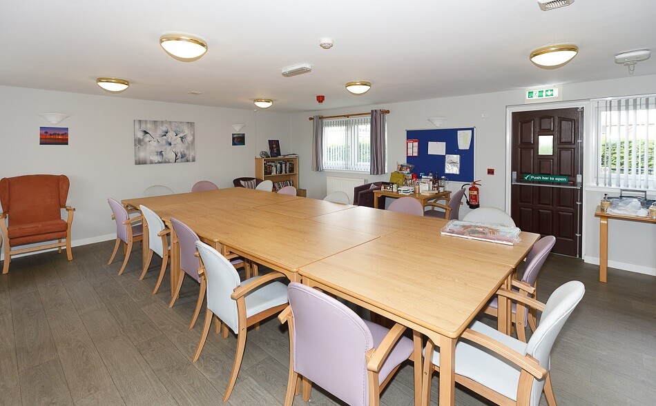 Dining table and chairs in the communal lounge at Sea Road