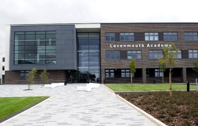 he exterior of Levenmouth Academy, a modern building with a mix of dark brick and large glass windows.