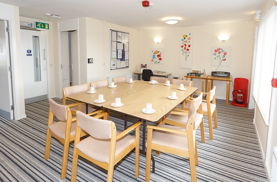 Communal dining area at McFarlane Court, with long table and chairs from an alternate angle