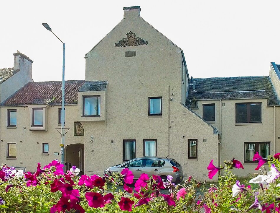 Exterior of Tolbooth Close, showing communal walkway into the complex and flowers in the foreground