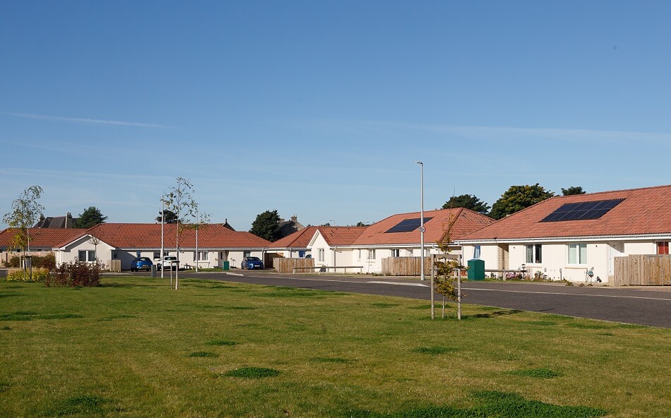 Large communal grassy area with small road leading to each of the bungalows at Methil Care Village
