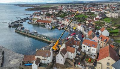 A crane in position between houses on the Pittenweem coast working to repair the coastal defence.
