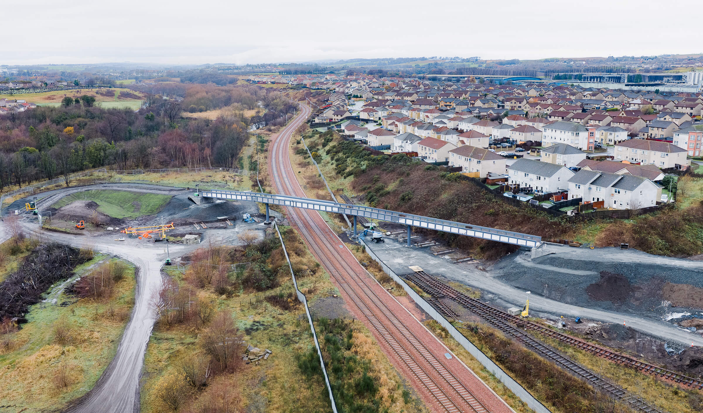 Construction site with the new Mountfleurie pedestrian bridge over railway tracks, surrounded by houses and roads.