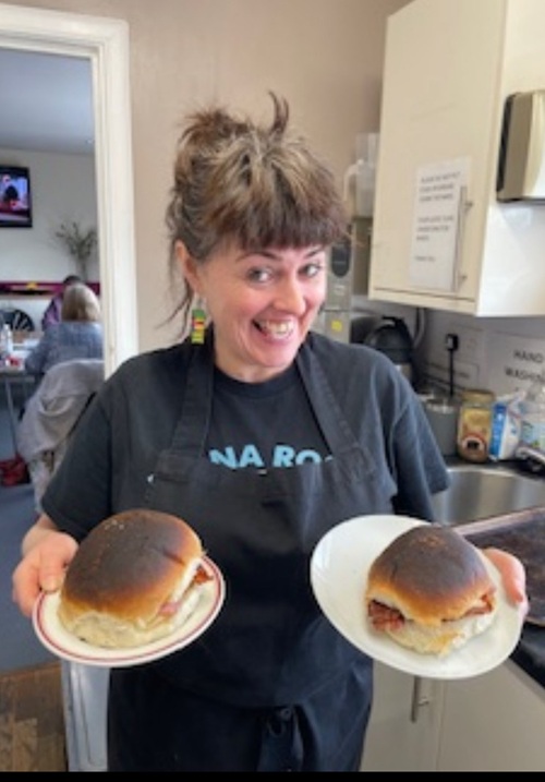 Lady standing holding a plate in each hand with a roll on them