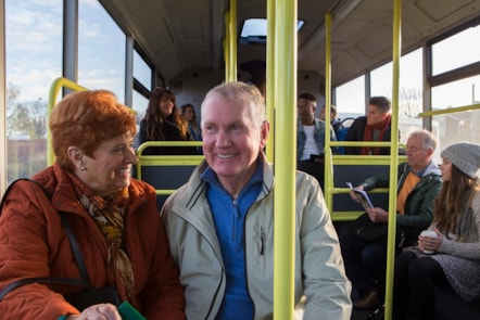 A woman and man sit next to each other on a bus service, smiling and laughing. - Council wants local views on supported bus services
