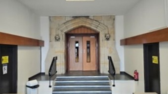 Main entrance with a short flight of stairs leading to double wooden doors set within a decorative stone archway.