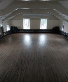 Victory memorial hall with a large wooden floor and chairs lined up along the walls under a vaulted ceiling.