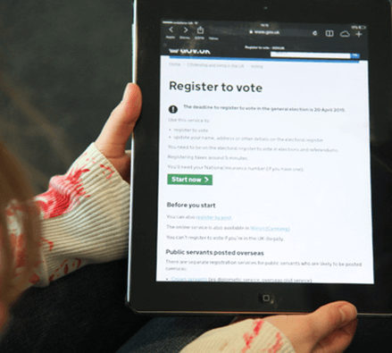 Image of someone holding a tablet, with the Gov.uk 'Register to Vote' page on screen.